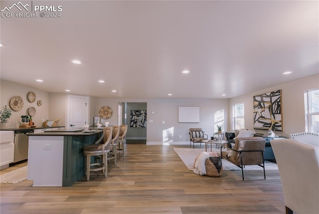 interior space featuring a kitchen bar, white cabinetry, light hardwood / wood-style flooring, and stainless steel dishwasher