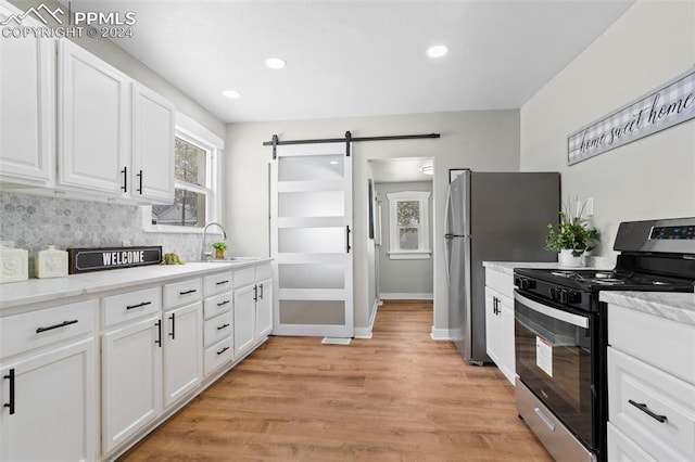 kitchen featuring backsplash, a barn door, light hardwood / wood-style floors, white cabinetry, and stainless steel range with gas stovetop