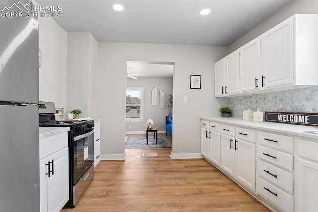 kitchen featuring stainless steel refrigerator, light hardwood / wood-style flooring, white cabinets, and black gas range oven