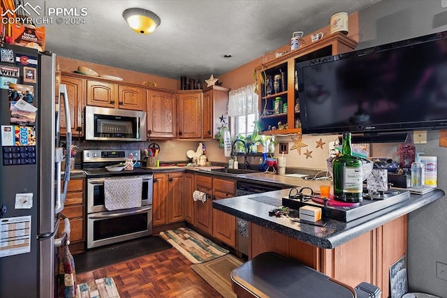 kitchen featuring kitchen peninsula, appliances with stainless steel finishes, dark parquet flooring, a breakfast bar, and sink