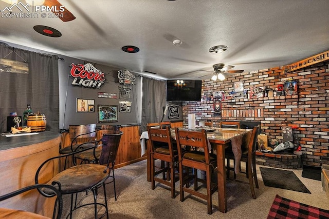 carpeted dining area with bar, a textured ceiling, ceiling fan, and wooden walls