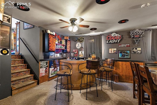 bar with carpet, ceiling fan, a textured ceiling, and wooden walls