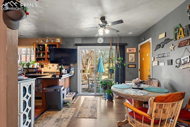 dining space with a textured ceiling, light wood-type flooring, and ceiling fan