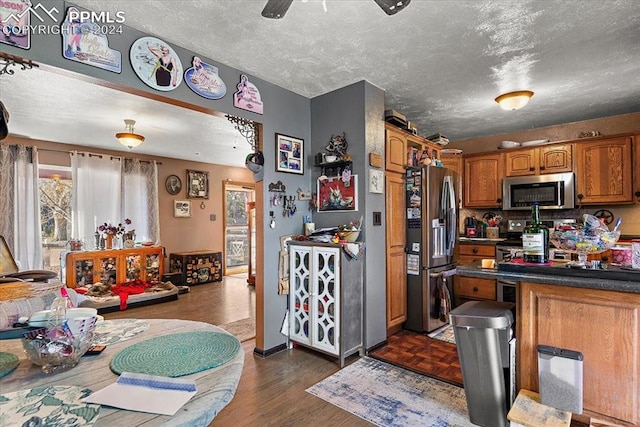 kitchen featuring a textured ceiling, stainless steel appliances, dark hardwood / wood-style floors, and ceiling fan