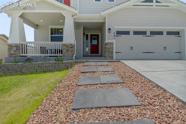 doorway to property with covered porch and a garage