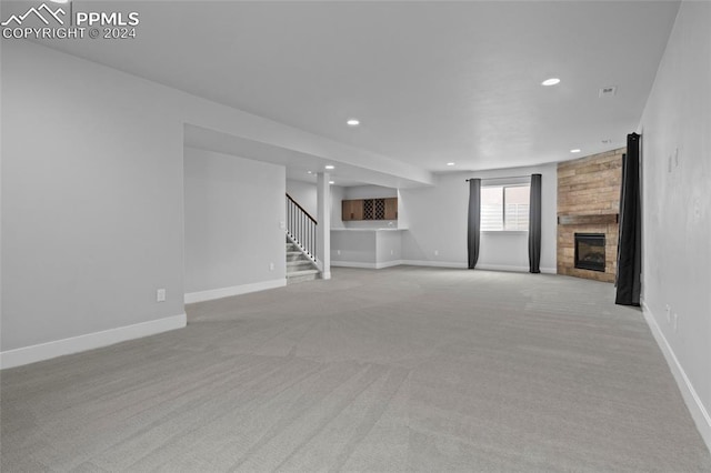 unfurnished living room featuring light carpet and a large fireplace