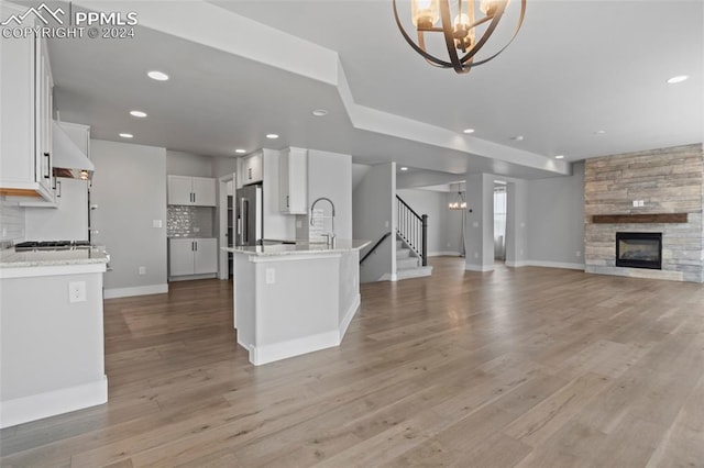 kitchen with backsplash, a tile fireplace, white cabinetry, and light hardwood / wood-style floors