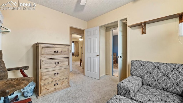 sitting room featuring a textured ceiling, light colored carpet, and ceiling fan