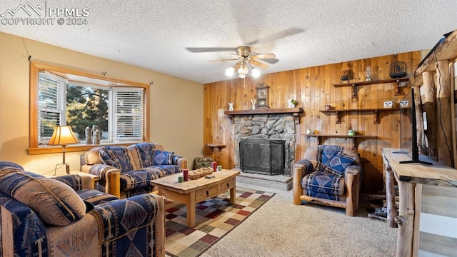 living room featuring carpet flooring, a textured ceiling, wooden walls, and a stone fireplace