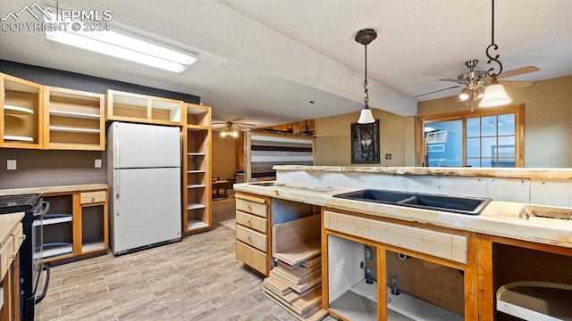 kitchen featuring hanging light fixtures, light hardwood / wood-style floors, black range, and white fridge