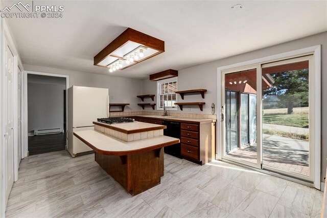 kitchen with a baseboard radiator, stainless steel gas stovetop, a center island, a breakfast bar area, and white fridge