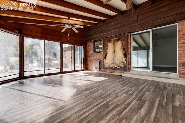 unfurnished living room with hardwood / wood-style floors, wooden walls, ceiling fan, and beam ceiling