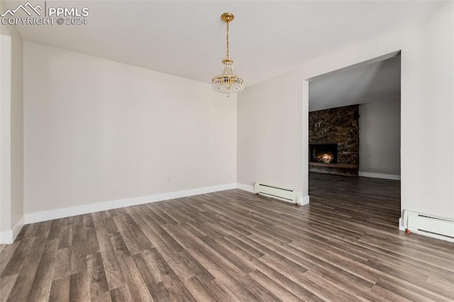 unfurnished room featuring a baseboard heating unit, a fireplace, dark hardwood / wood-style floors, and an inviting chandelier