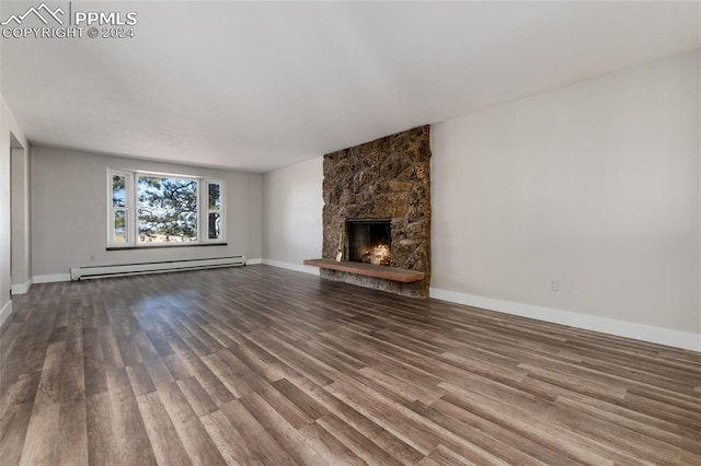 unfurnished living room with hardwood / wood-style flooring, a stone fireplace, and a baseboard radiator