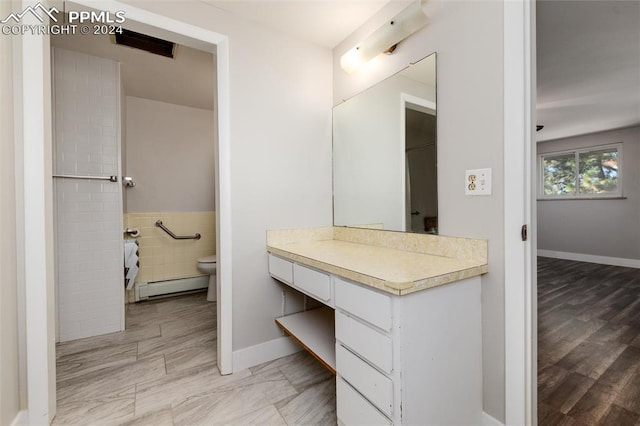 bathroom featuring vanity, hardwood / wood-style flooring, a baseboard radiator, and toilet