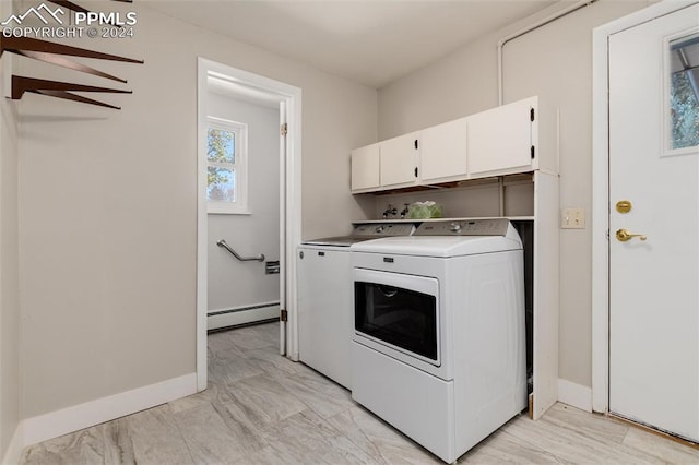 laundry area with baseboard heating, cabinets, and washer and dryer