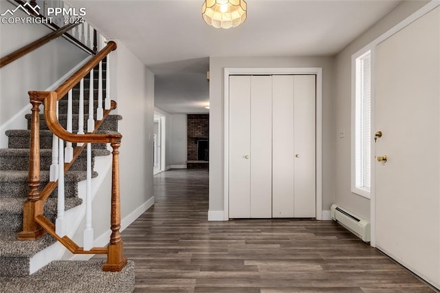 foyer entrance with a brick fireplace, a baseboard radiator, and dark hardwood / wood-style flooring