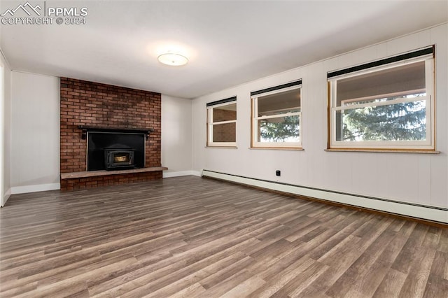 unfurnished living room featuring a wood stove, hardwood / wood-style floors, and baseboard heating