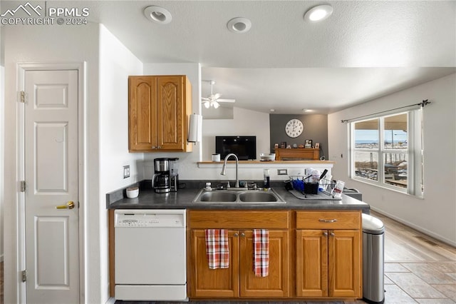 kitchen featuring dishwasher, sink, vaulted ceiling, ceiling fan, and a textured ceiling