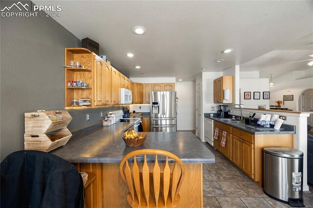 kitchen with kitchen peninsula, stainless steel appliances, ceiling fan, and sink