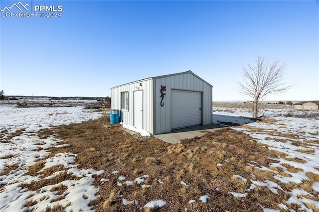 snow covered structure with a garage