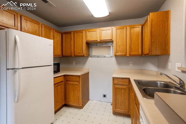 kitchen featuring a textured ceiling, sink, and white fridge