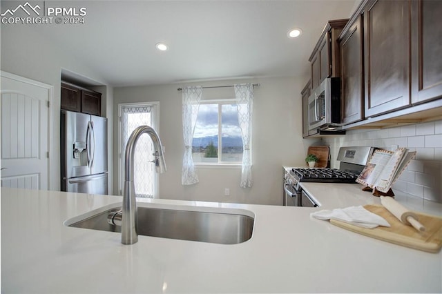 kitchen featuring dark brown cabinetry, decorative backsplash, stainless steel appliances, and sink