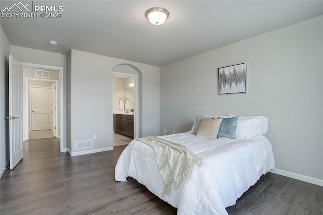 bedroom featuring dark wood-type flooring and ensuite bath