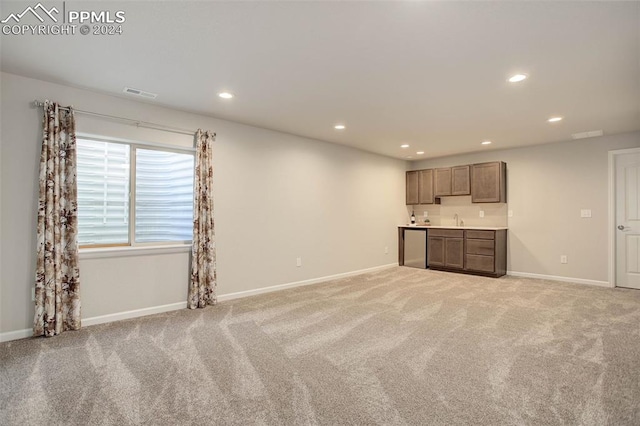 unfurnished living room featuring light colored carpet and sink