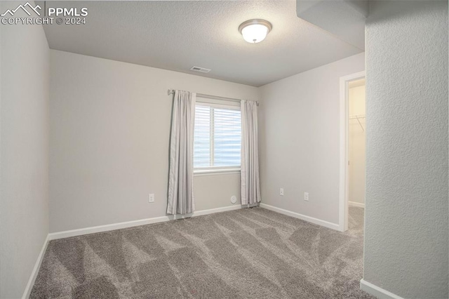 spare room featuring a textured ceiling and carpet flooring