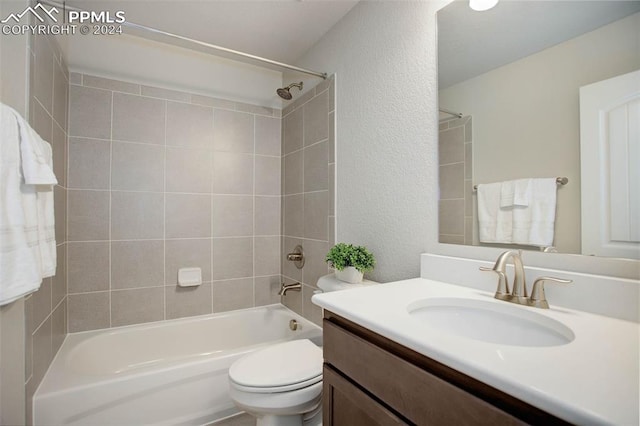 full bathroom featuring vanity, tiled shower / bath combo, and toilet