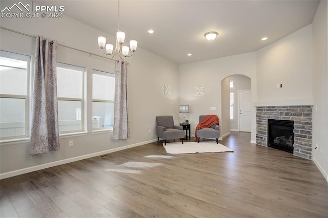 sitting room with a stone fireplace, an inviting chandelier, and hardwood / wood-style flooring