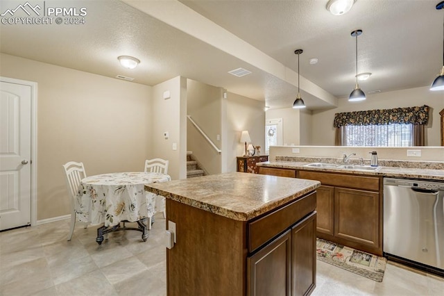 kitchen featuring a center island, a textured ceiling, sink, stainless steel dishwasher, and decorative light fixtures