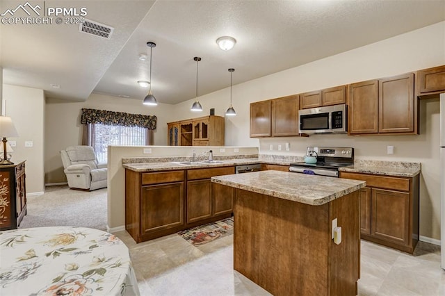 kitchen with stainless steel appliances, decorative light fixtures, sink, kitchen peninsula, and a center island