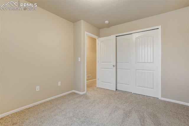 unfurnished bedroom featuring a closet and light colored carpet