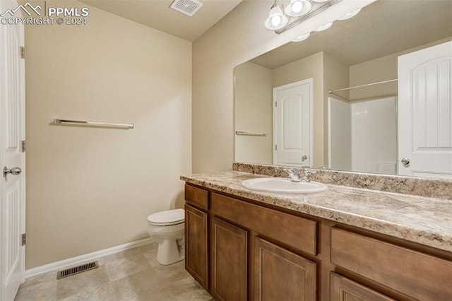 bathroom with toilet, a shower, vanity, and tile patterned floors