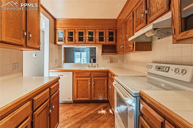 kitchen with decorative backsplash, sink, white appliances, and light wood-type flooring