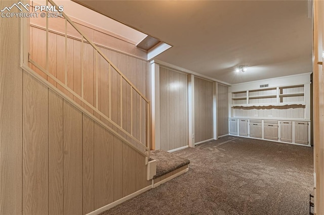 basement with dark carpet and wood walls