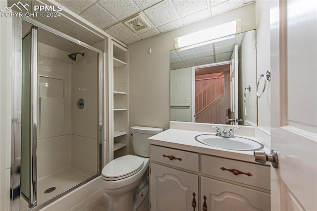 bathroom with walk in shower, tile patterned floors, toilet, a paneled ceiling, and vanity