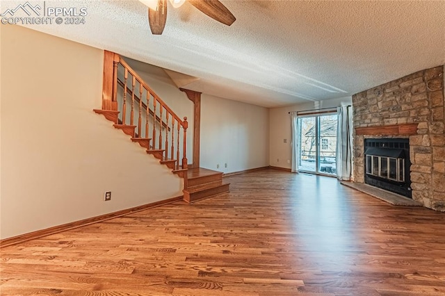 unfurnished living room featuring hardwood / wood-style flooring, a fireplace, ceiling fan, and a textured ceiling