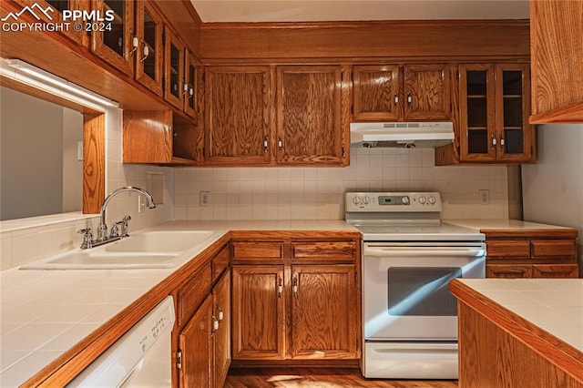 kitchen featuring decorative backsplash, white appliances, tile counters, and sink