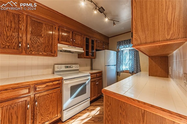 kitchen featuring decorative backsplash, dark hardwood / wood-style flooring, tile counters, white range with electric cooktop, and fridge