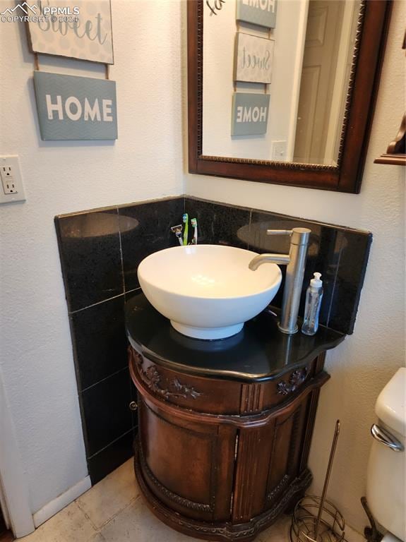 bathroom featuring tile patterned floors, vanity, tile walls, and toilet