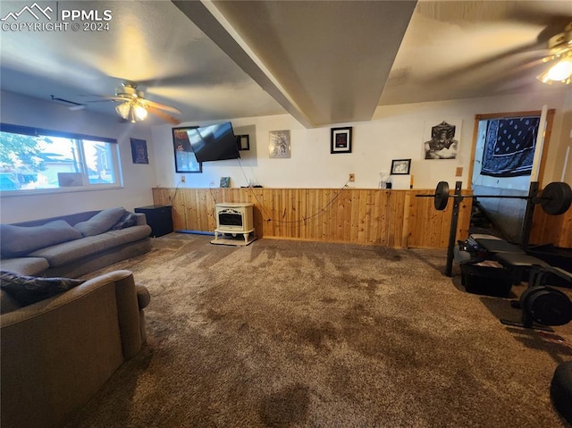 living room with carpet, ceiling fan, and wood walls