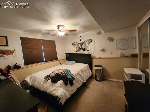 carpeted bedroom with ceiling fan and a textured ceiling