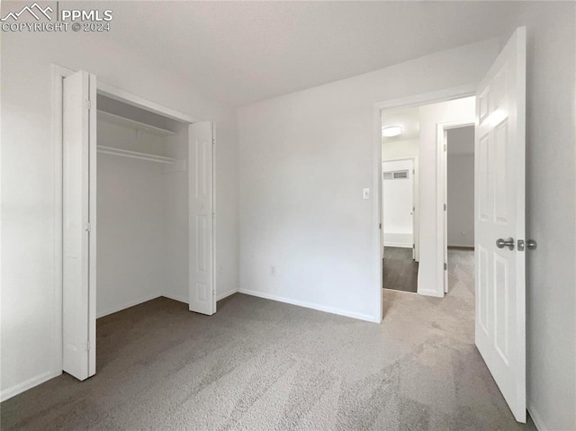 unfurnished bedroom with light colored carpet and a closet