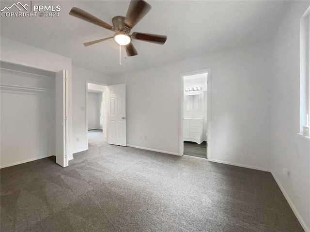 unfurnished bedroom with a closet, ceiling fan, dark carpet, and connected bathroom