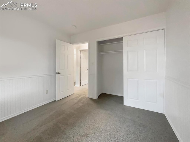 unfurnished bedroom with a closet and dark colored carpet