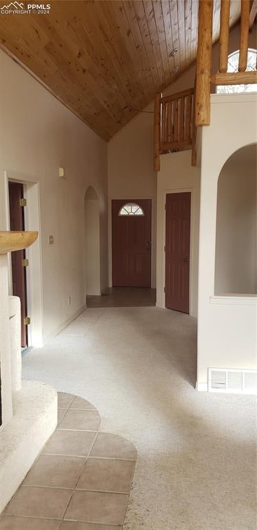 interior space with carpet, wooden ceiling, and high vaulted ceiling