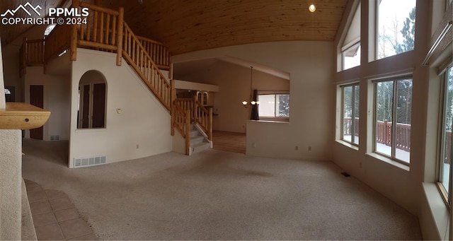 unfurnished living room with a notable chandelier, a healthy amount of sunlight, and high vaulted ceiling